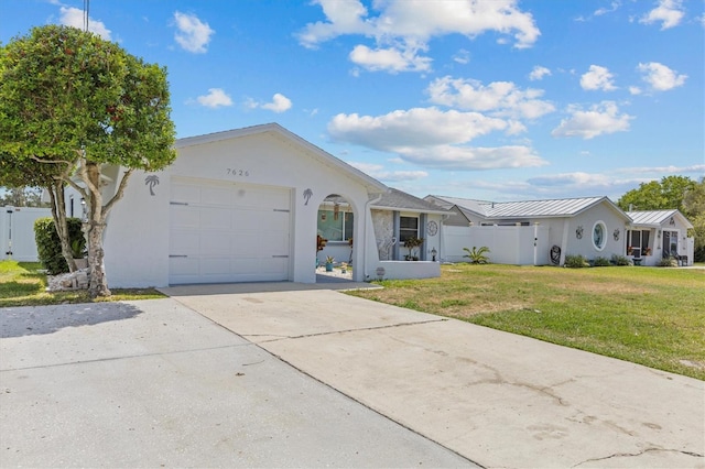 ranch-style home featuring concrete driveway, an attached garage, stucco siding, and a front lawn
