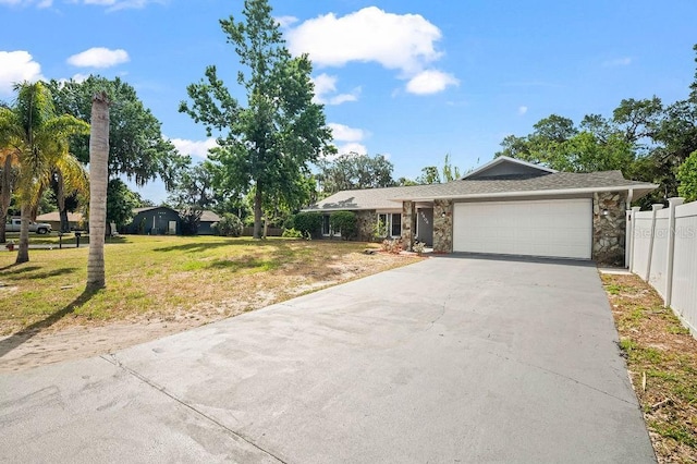 ranch-style house featuring fence, a garage, driveway, and stone siding