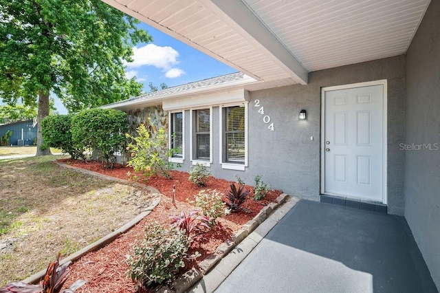 doorway to property featuring stucco siding