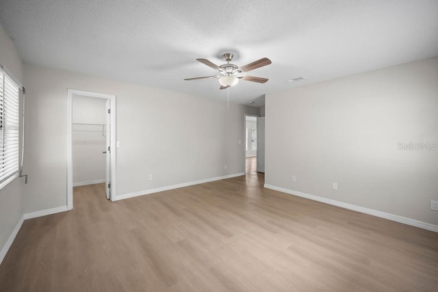 spare room with visible vents, baseboards, ceiling fan, a textured ceiling, and light wood finished floors