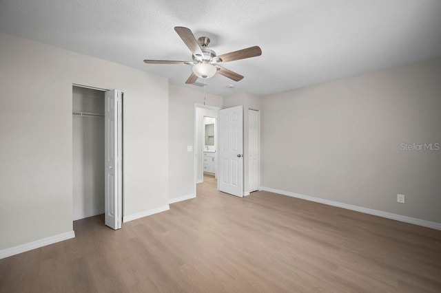 unfurnished bedroom featuring light wood-style floors, baseboards, ceiling fan, and two closets