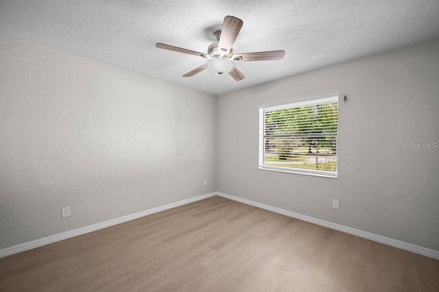 spare room with baseboards, ceiling fan, a textured ceiling, and wood finished floors
