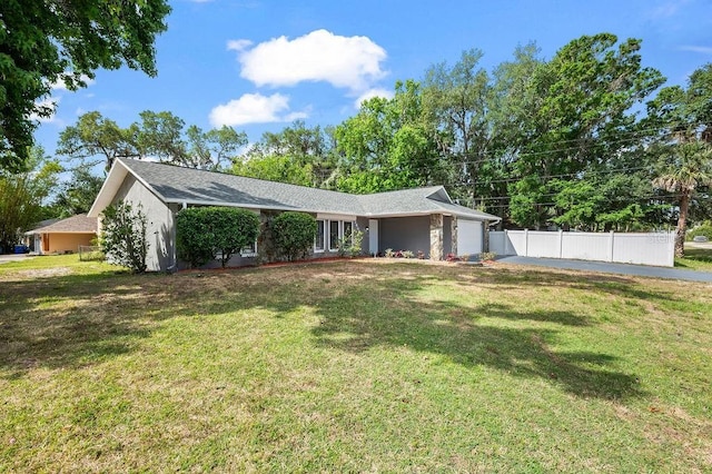 exterior space with fence, an attached garage, stucco siding, and a front lawn