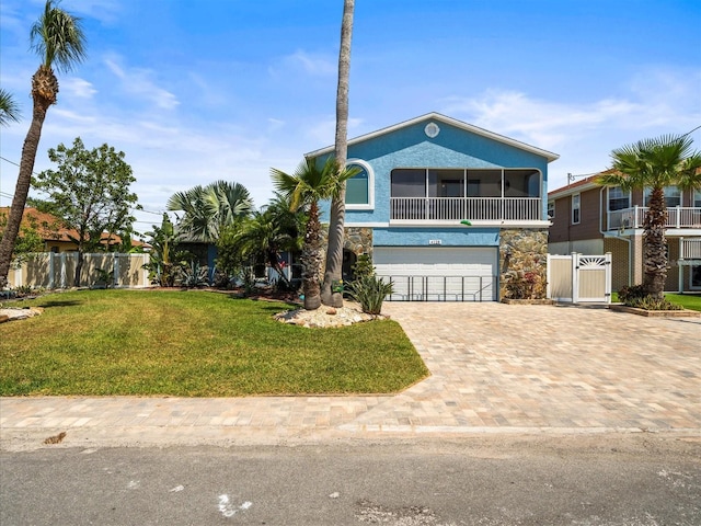raised beach house with a gate, a garage, fence, a front lawn, and driveway