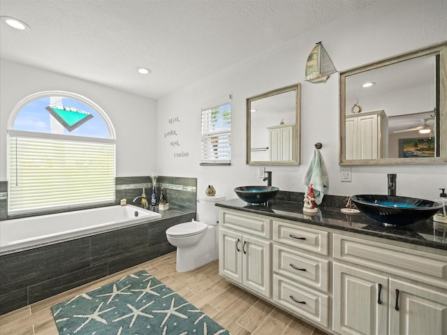bathroom with a sink, toilet, a bath, and wood finished floors