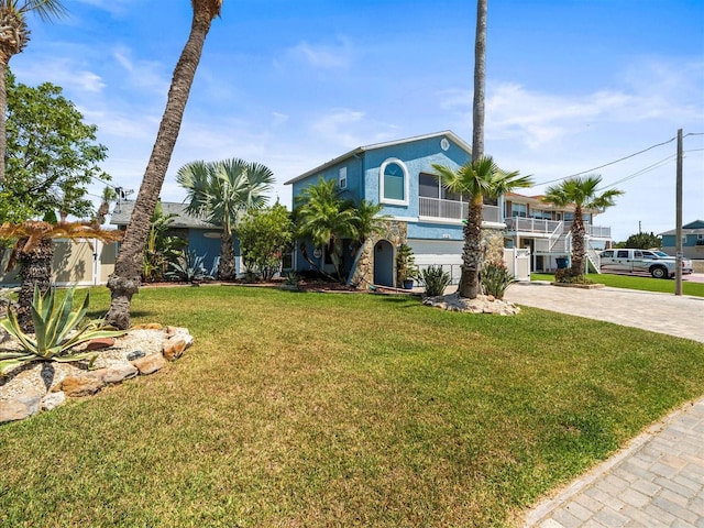 beach home with stucco siding, a front lawn, and decorative driveway