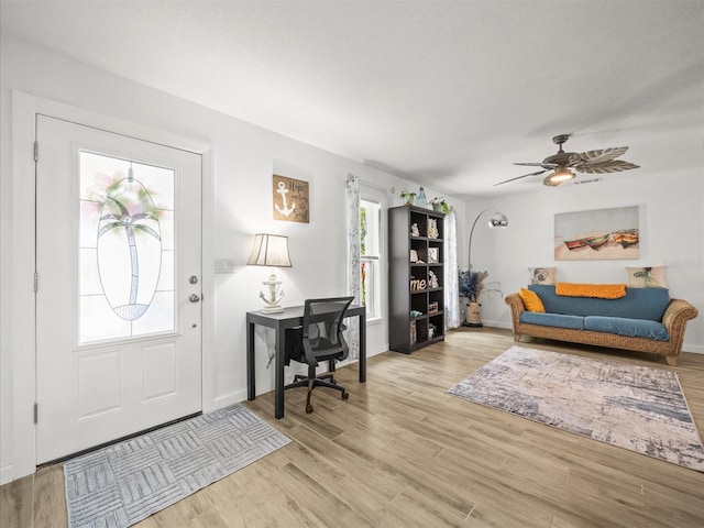 foyer entrance featuring baseboards, light wood finished floors, and ceiling fan