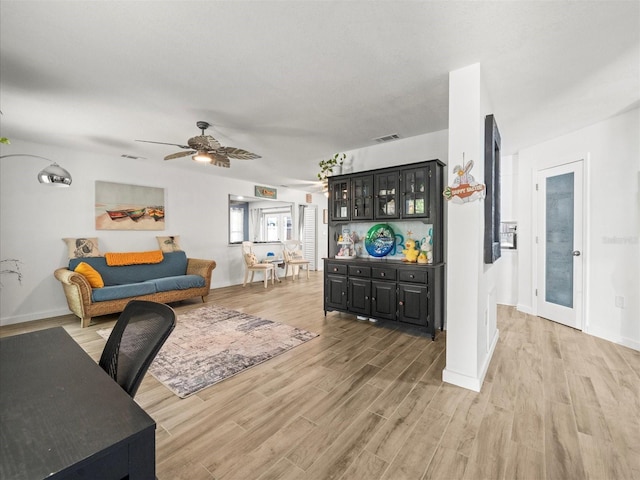 living area with ceiling fan, light wood-style flooring, baseboards, and visible vents