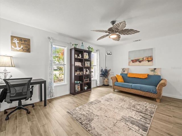 office area featuring baseboards, a ceiling fan, visible vents, and wood finished floors