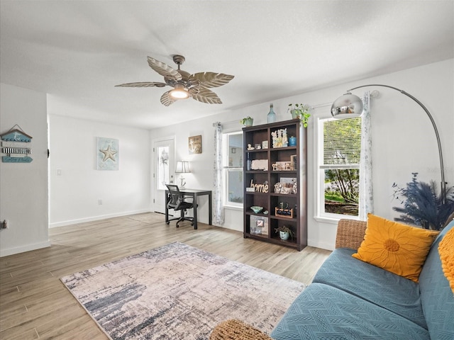 living room featuring baseboards, wood finished floors, and a ceiling fan