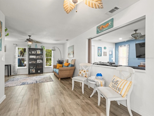 sitting room with ceiling fan, baseboards, visible vents, and wood finished floors