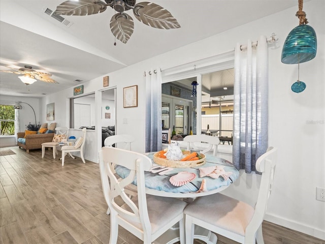 dining space featuring a ceiling fan, baseboards, visible vents, and wood finished floors