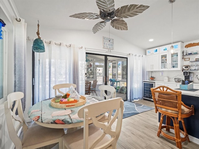 dining room featuring ceiling fan, wine cooler, light wood-style floors, vaulted ceiling, and recessed lighting
