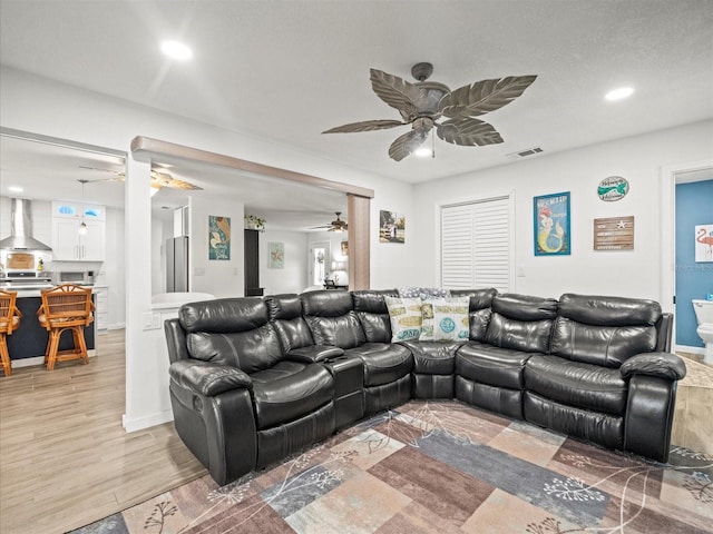 living area featuring visible vents, light wood-style flooring, a ceiling fan, and recessed lighting