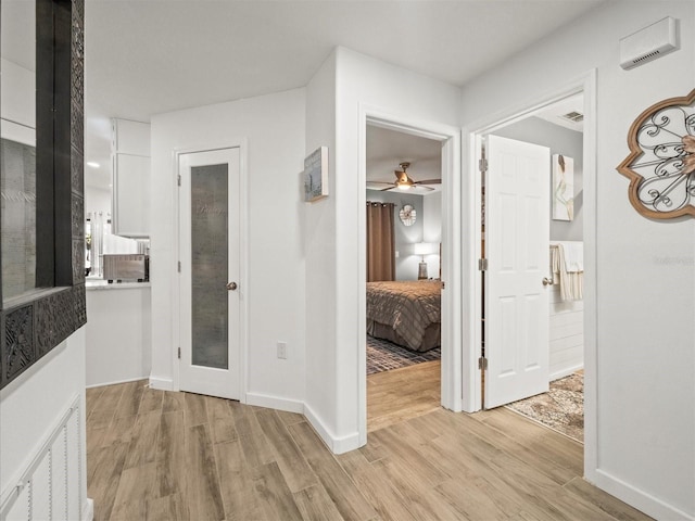 corridor with light wood-type flooring, visible vents, and baseboards