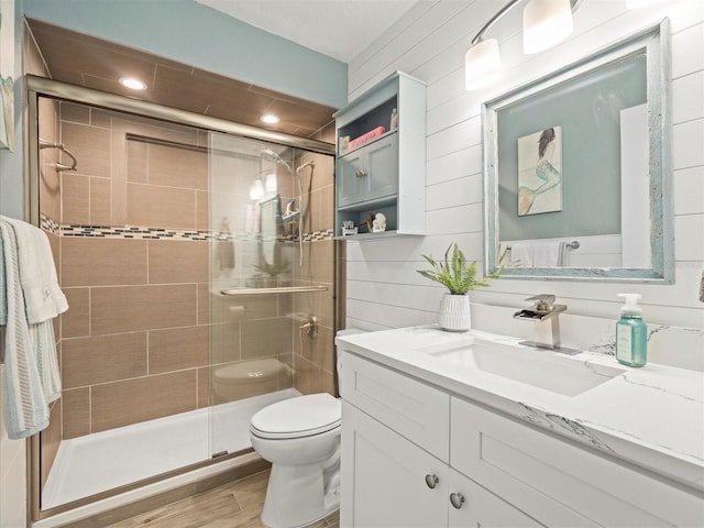 full bath featuring a stall shower, vanity, toilet, and wood finished floors