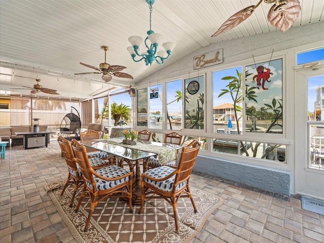 sunroom / solarium featuring lofted ceiling, a healthy amount of sunlight, outdoor dining space, and ceiling fan with notable chandelier