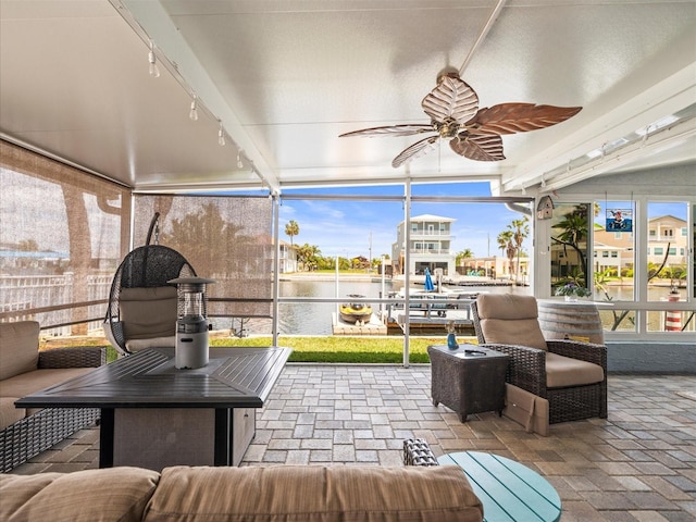 sunroom featuring a water view, a ceiling fan, and track lighting