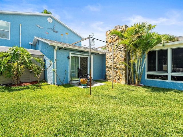 rear view of house with a yard and stucco siding