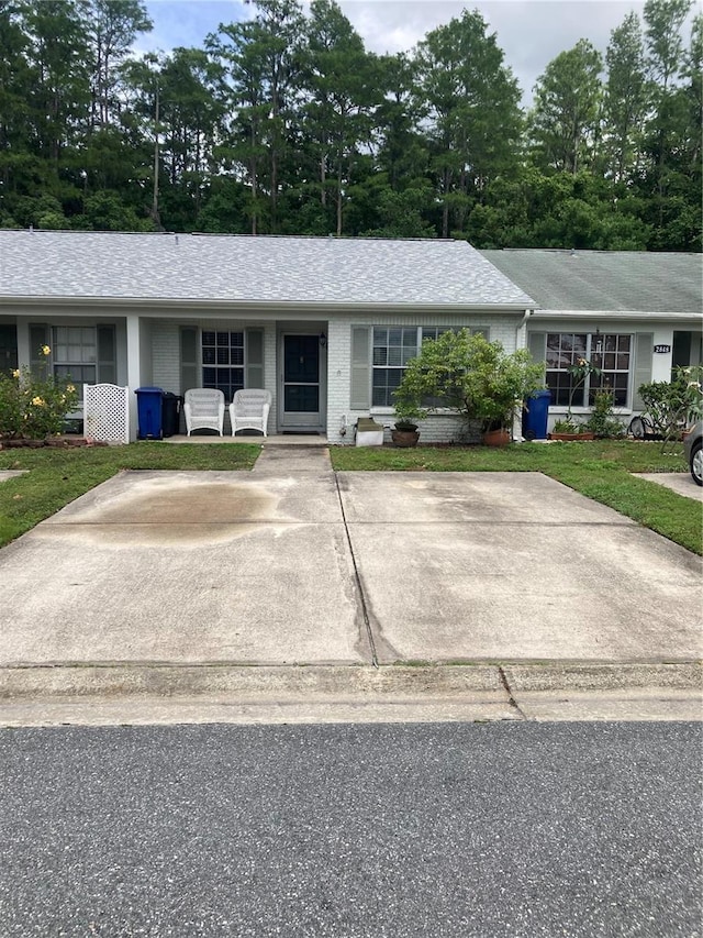 2850 Westmoreland Ct, New Port Richey, FL 34655 - ranch-style house featuring brick siding, a shingled roof, and view of wooded area