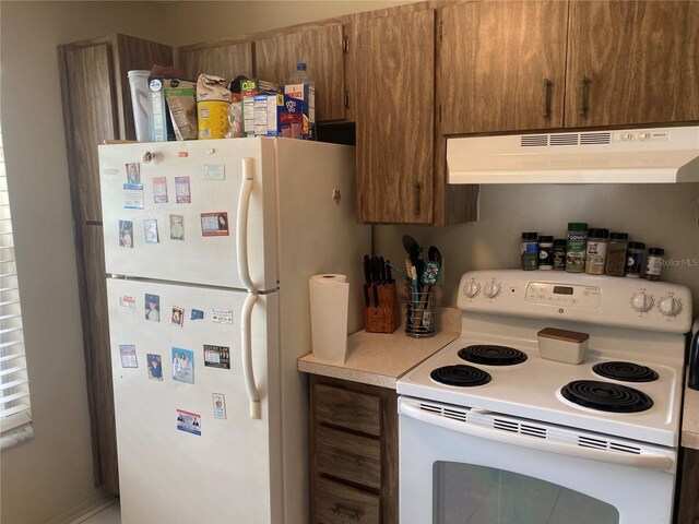 2850 Westmoreland Ct, New Port Richey, FL 34655 - kitchen featuring white appliances, exhaust hood, light countertops, and brown cabinetry