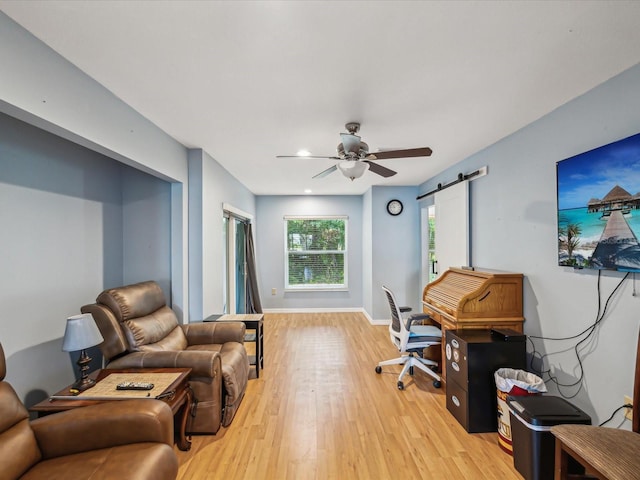 11512 Yellow Birch Ct, New Port Richey, FL 34654 - office space featuring light wood finished floors, a ceiling fan, a barn door, and baseboards
