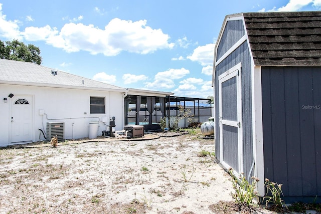exterior space with a sunroom, a storage shed, central AC, and an outdoor structure