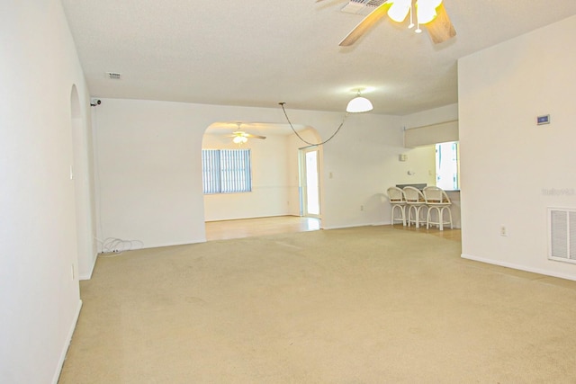 empty room with light colored carpet, visible vents, baseboards, and a ceiling fan