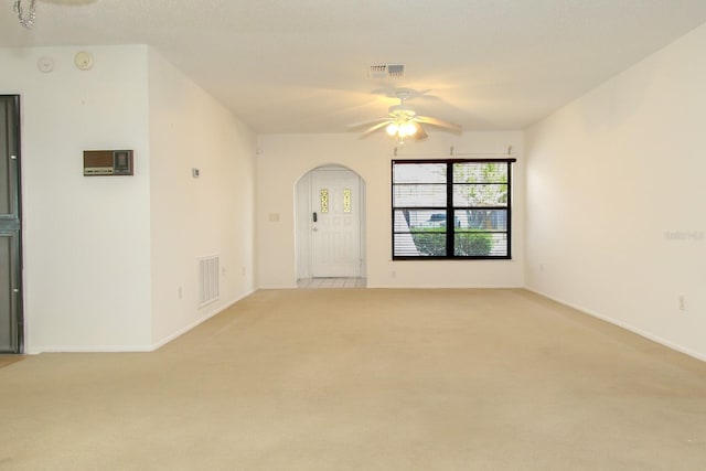 empty room featuring light colored carpet, visible vents, and a ceiling fan
