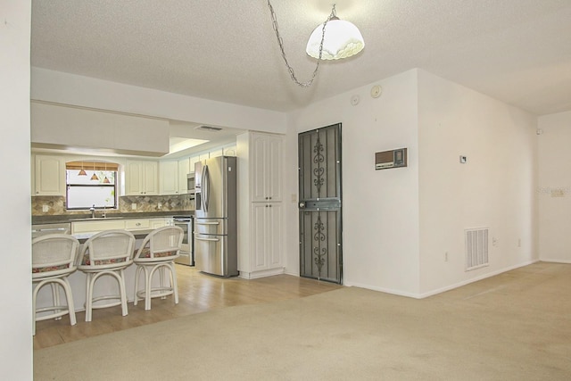kitchen featuring visible vents, a sink, a kitchen breakfast bar, backsplash, and stainless steel appliances