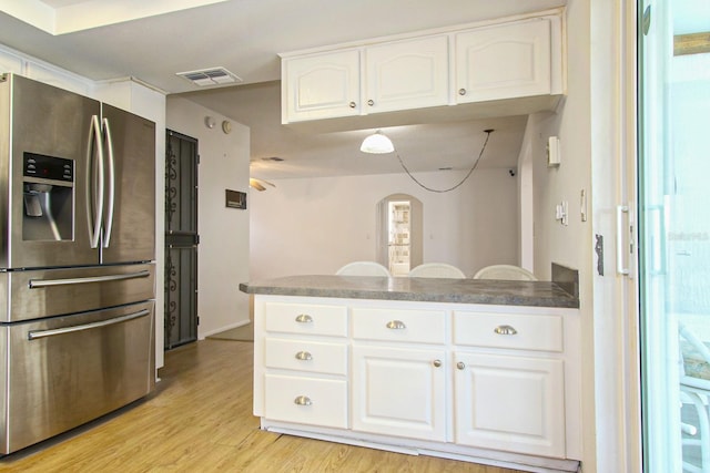 kitchen featuring a peninsula, stainless steel fridge, light wood-style flooring, white cabinets, and visible vents