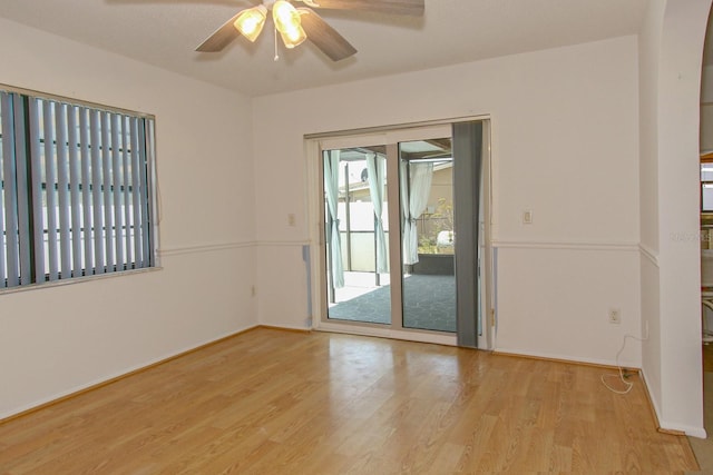empty room featuring ceiling fan, baseboards, and wood finished floors