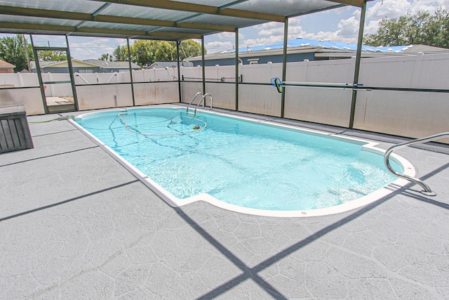 view of pool featuring a patio area, glass enclosure, a fenced in pool, and a fenced backyard