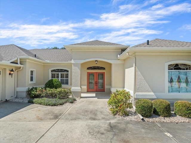 9216 Tarleton Cir, Weeki Wachee, FL 34613 - view of exterior entry featuring stucco siding, french doors, and a shingled roof