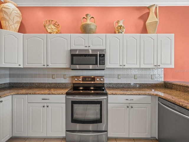 9216 Tarleton Cir, Weeki Wachee, FL 34613 - kitchen featuring light tile patterned floors, dark countertops, white cabinetry, backsplash, and appliances with stainless steel finishes