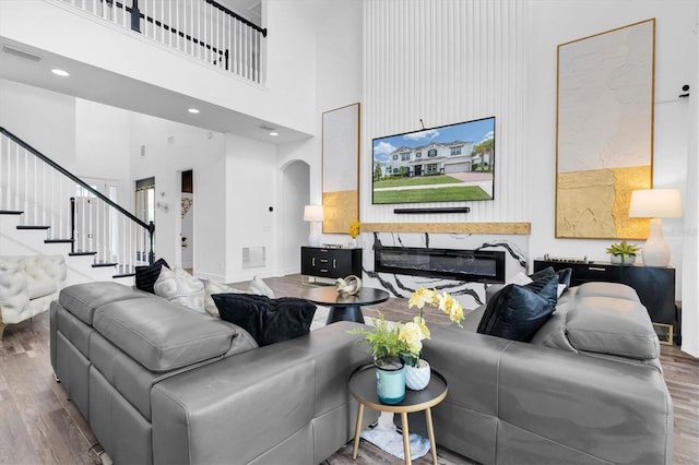 4188 Barbour Trl, Odessa, FL 33556 - living area with a towering ceiling, wood finished floors, arched walkways, stairs, and a glass covered fireplace