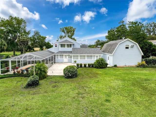 rear view of house featuring a shingled roof, a lanai, a gambrel roof, and a lawn