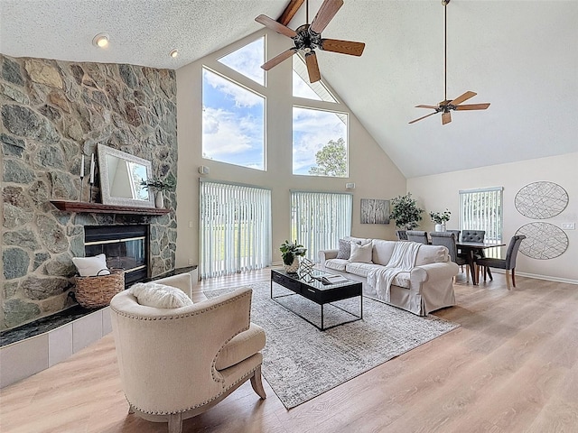 living room with plenty of natural light, a fireplace, a ceiling fan, and high vaulted ceiling