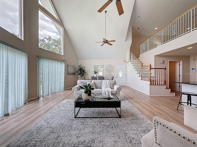 living room featuring stairs, high vaulted ceiling, a ceiling fan, and wood finished floors