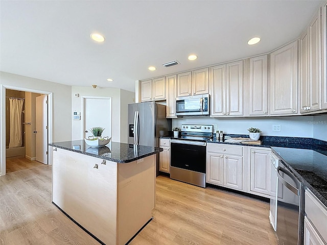kitchen with dark stone countertops, visible vents, light wood-style flooring, a center island, and appliances with stainless steel finishes