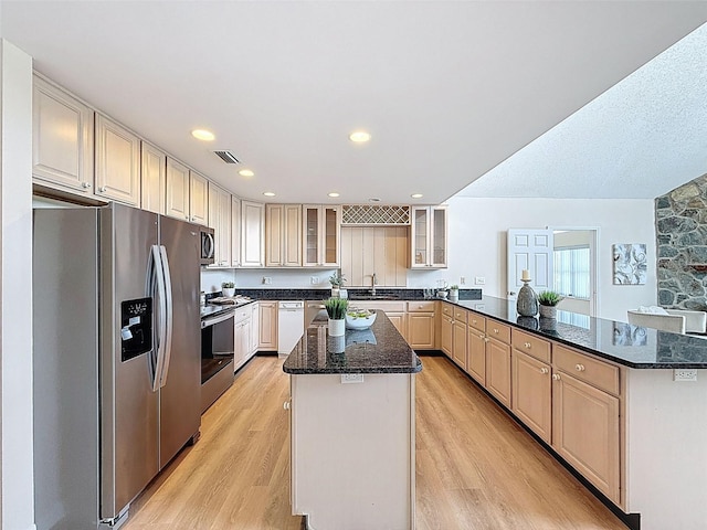 kitchen with a sink, a peninsula, stainless steel appliances, visible vents, and a kitchen island