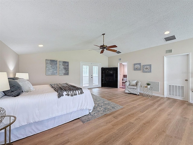 bedroom with vaulted ceiling, a textured ceiling, and visible vents