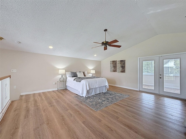 bedroom with wood finished floors, a textured ceiling, baseboards, access to outside, and lofted ceiling