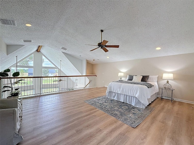 bedroom featuring baseboards, vaulted ceiling, visible vents, and wood finished floors