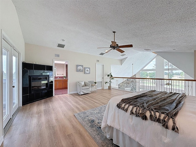 bedroom with a textured ceiling, visible vents, light wood-style flooring, and baseboards
