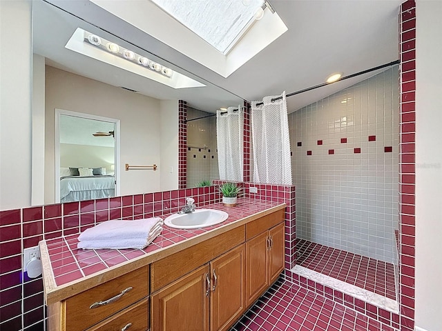 ensuite bathroom featuring a skylight, vanity, ensuite bath, tile patterned floors, and tiled shower