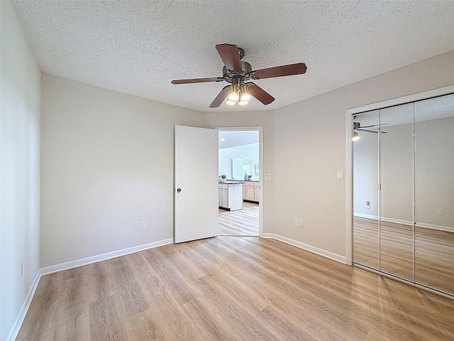 unfurnished bedroom with a closet, light wood-type flooring, baseboards, and a textured ceiling