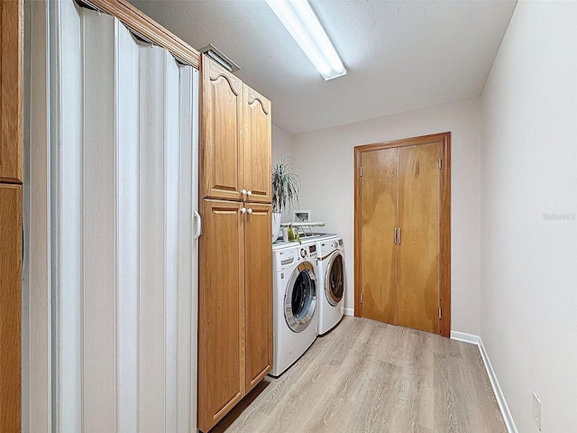 clothes washing area with washer and dryer, cabinet space, light wood-style flooring, and baseboards