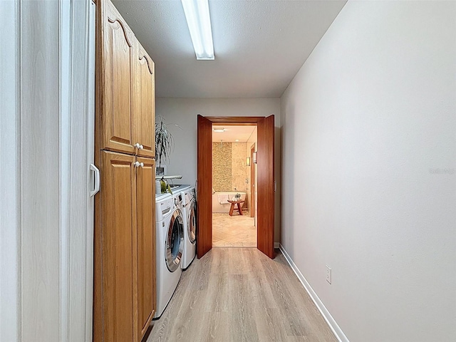 laundry area featuring separate washer and dryer, cabinet space, and light wood-type flooring