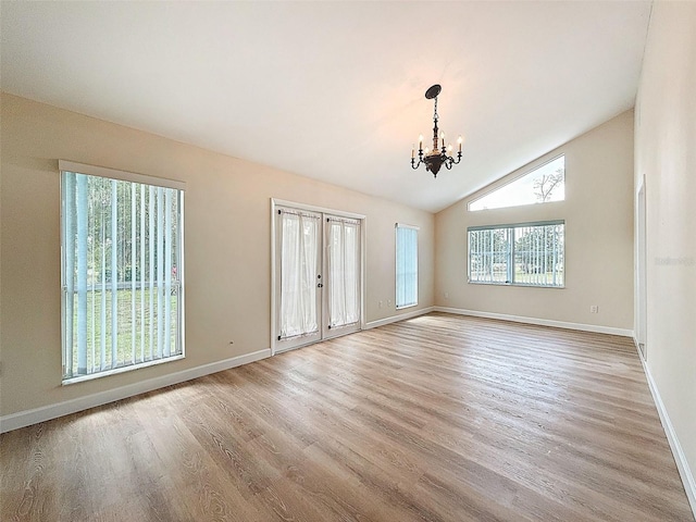 empty room with vaulted ceiling, a chandelier, baseboards, and wood finished floors